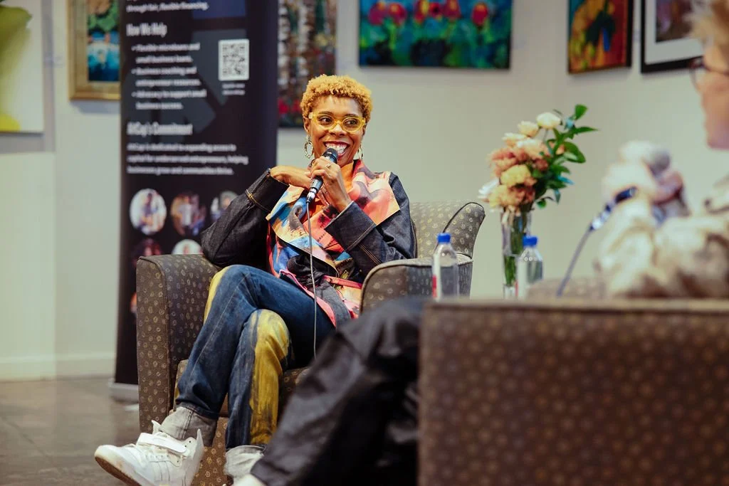 Seated African American woman holds microphone smiling.
