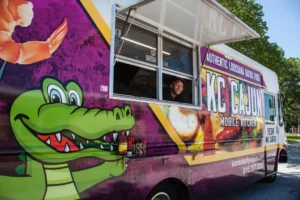 Image shows a man sticking his head out the service window of the KC Cajun food truck.