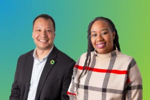 Image shows a man and a woman posing for a headshot in front of a blue to green gradient backdrop.
