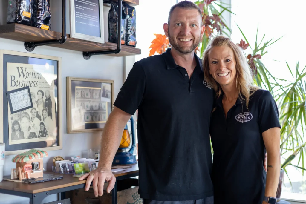 Image shows a man and woman posing closely together inside their small business restaurant
