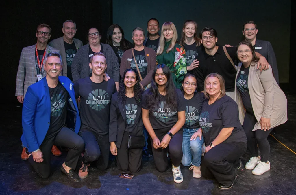 Image shows group of people smiling on a stage.