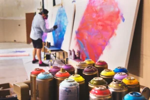 Image shows a man spray painting inside studio