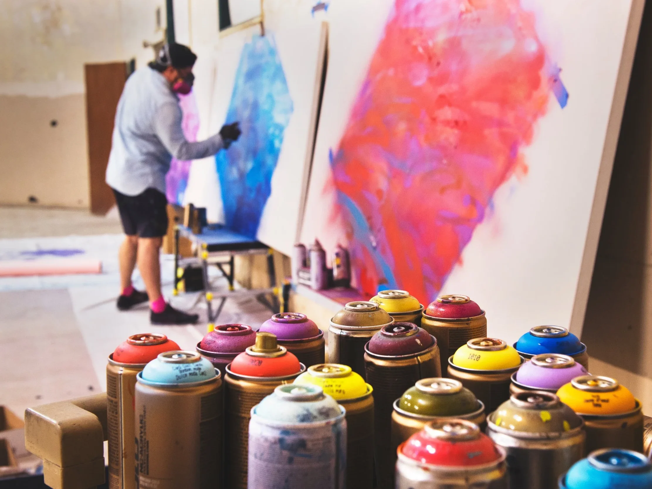 Image shows a man spray painting inside studio
