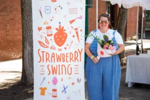 Image shows a woman standing outside holding flowers next to a retractable banner.